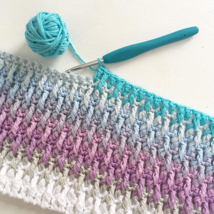 the crochet stitch is being worked on with a blue handled knitting needle and yarn ball