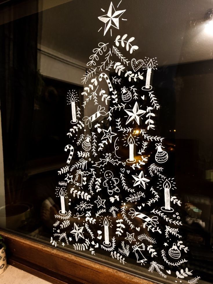 a christmas tree made out of cutouts in front of a glass window with ornaments on it