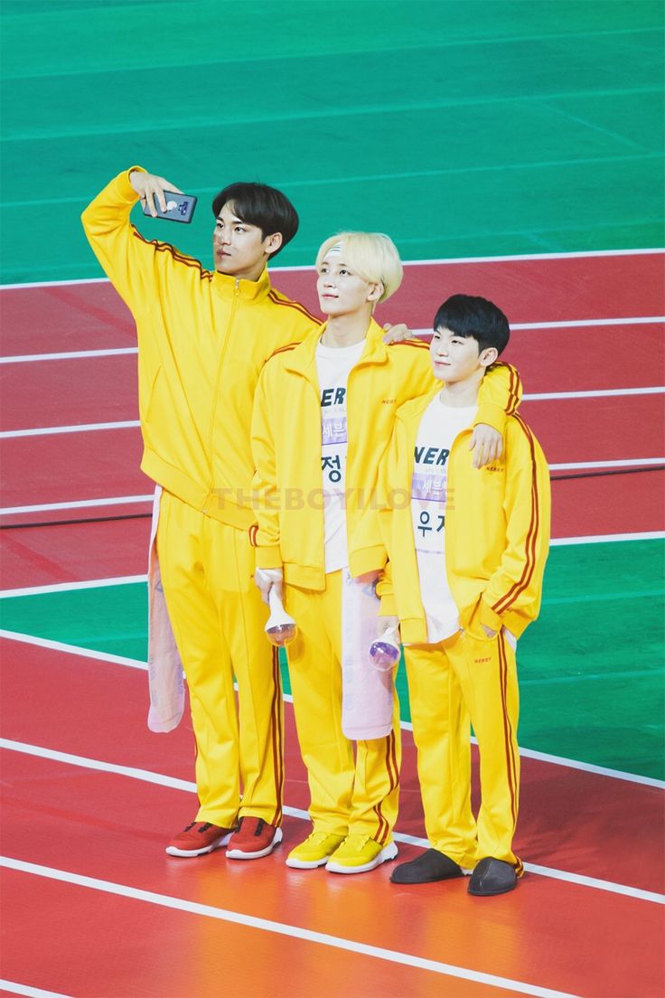 three young men in yellow outfits standing next to each other on a red and green track