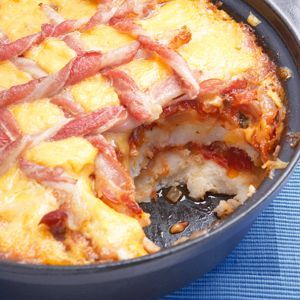 bacon and cheese casserole in a cast iron skillet on a blue mat