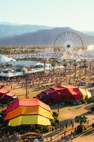 an aerial view of a carnival with tents, ferris wheel and mountains in the background