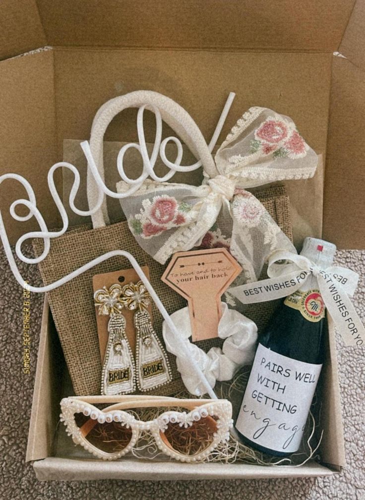 an open box with some items in it on the floor next to a bottle of wine