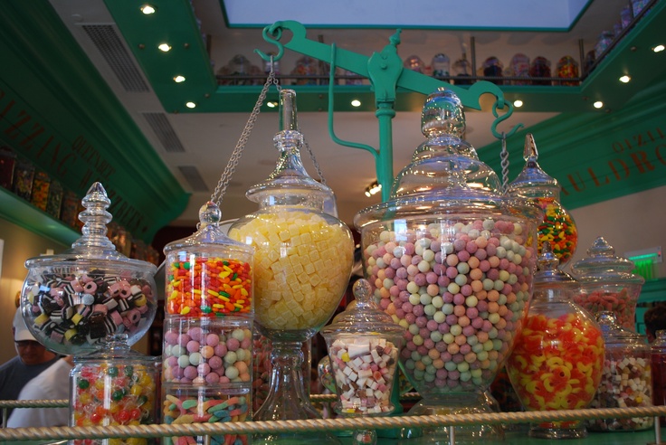 many different types of candies in glass jars on a shelf at a candy store