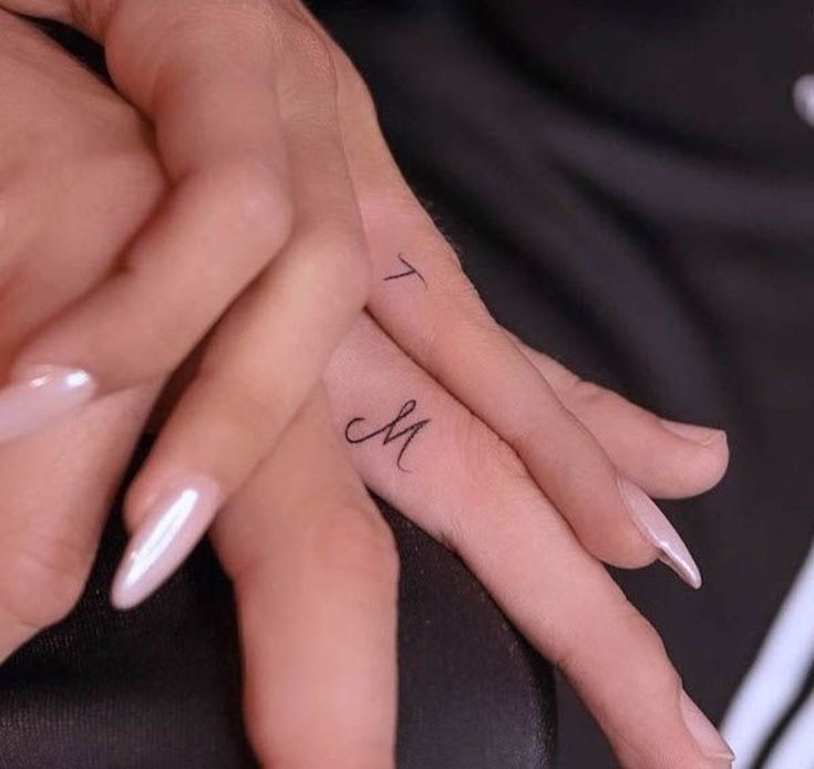 two hands holding each other with the word love tattooed on their thumbnails and fingers