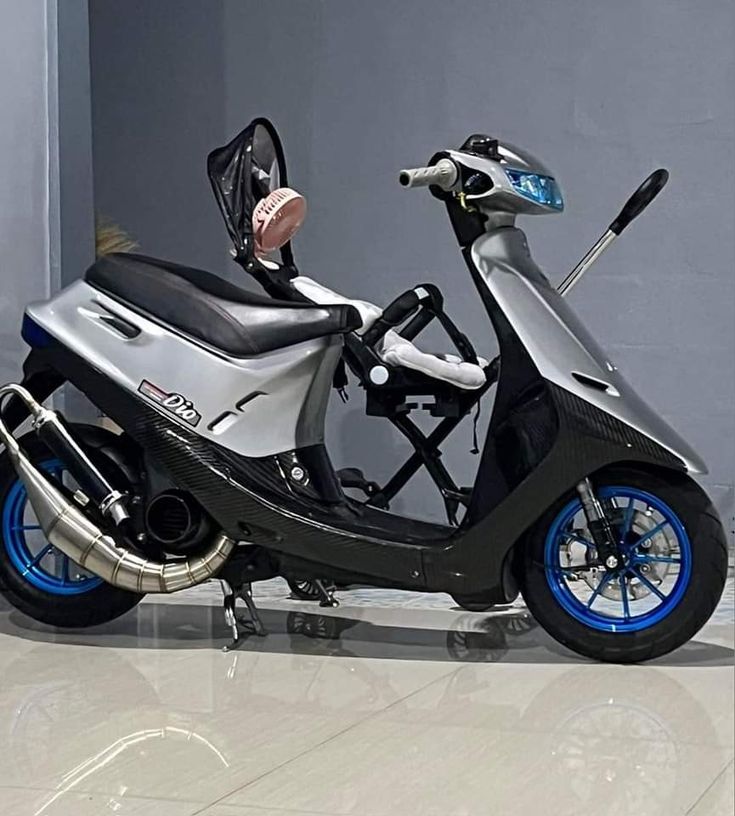 a scooter is parked on the floor in front of a gray wall with blue rims