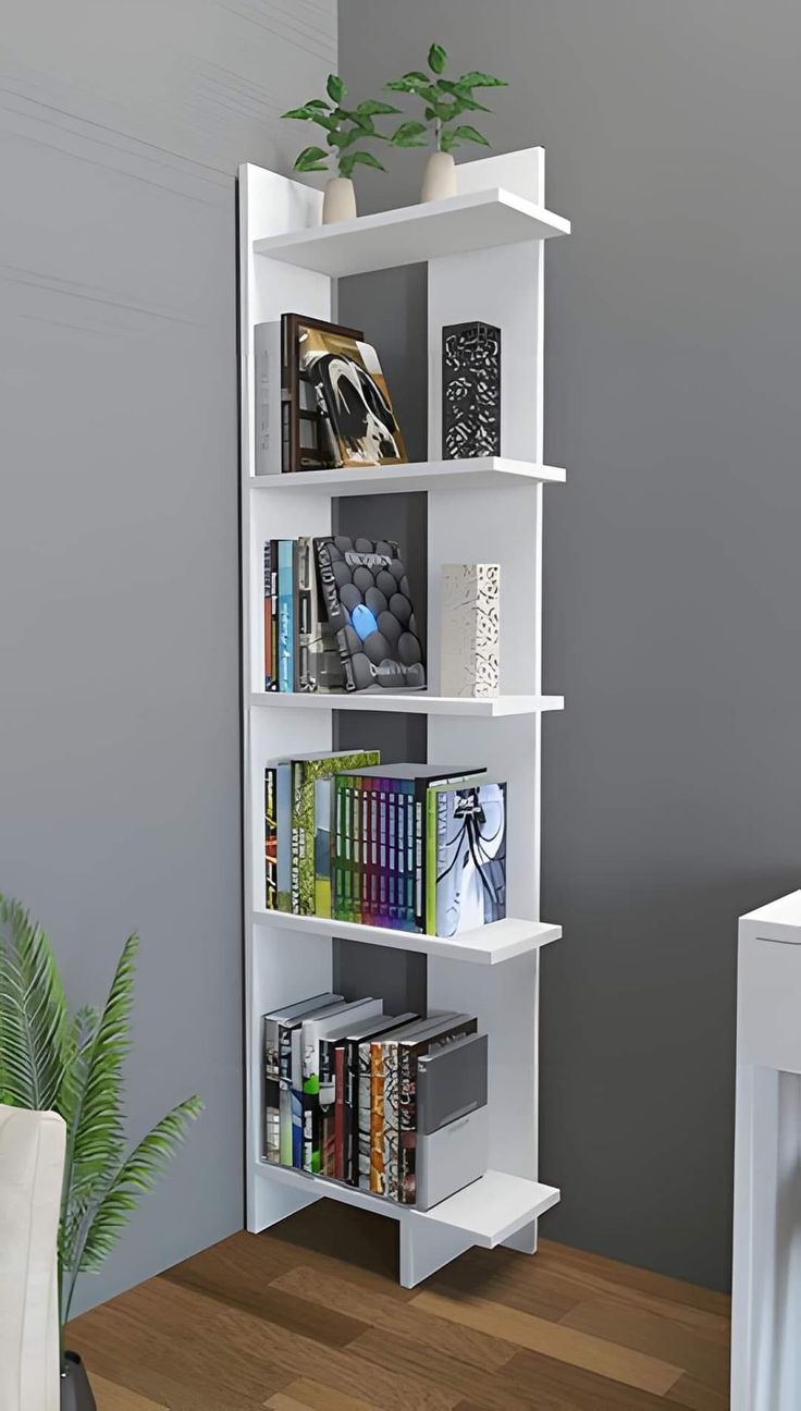 a white book shelf filled with books next to a plant on top of a wooden table