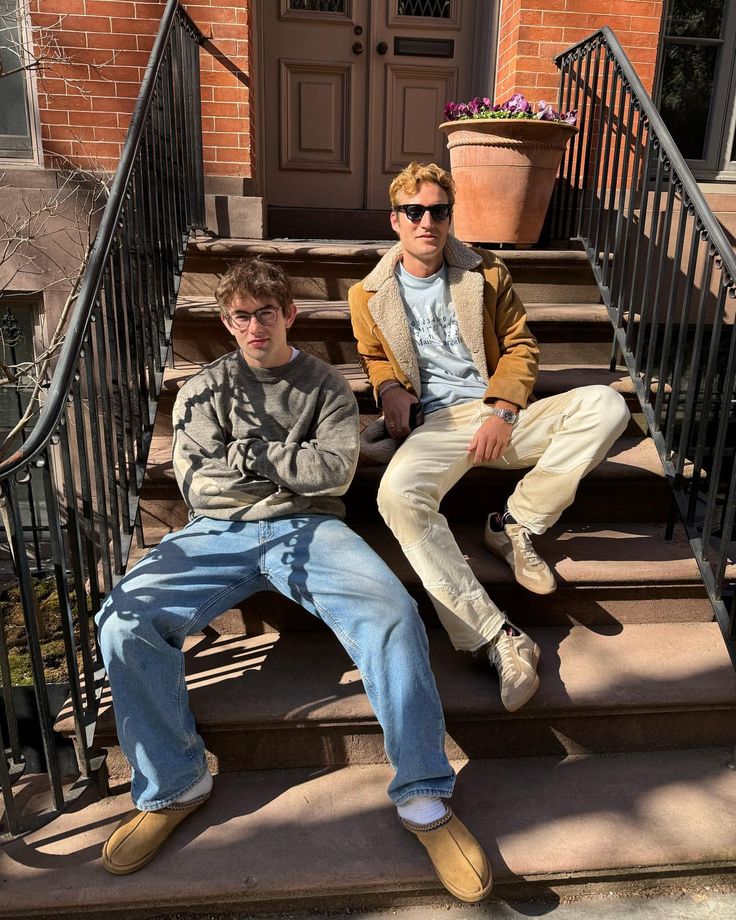 two young men sitting on the steps of a house