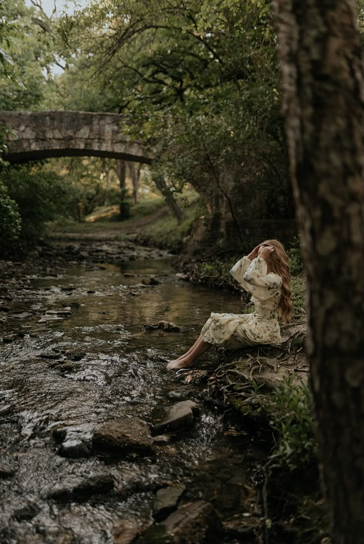 a woman sitting on the edge of a river