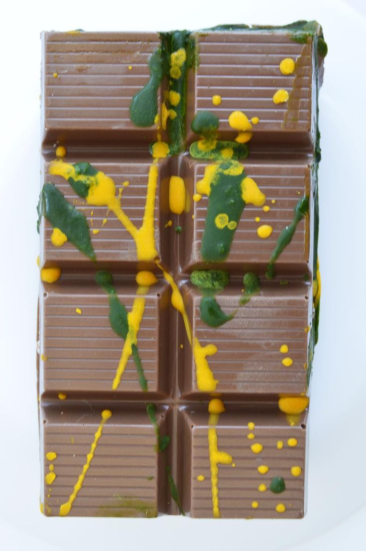 a chocolate bar with yellow paint splattered on it's sides and green leaves in the middle