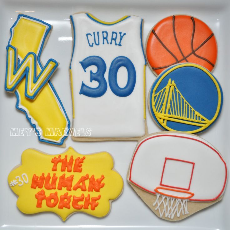 decorated cookies in the shape of sports jerseys and basketballs are on a white platter