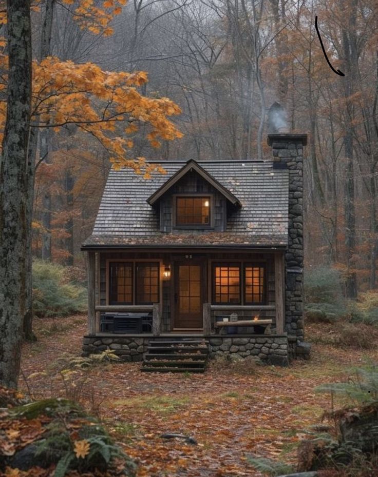 a small cabin in the woods surrounded by trees and leaves with fall foliage around it