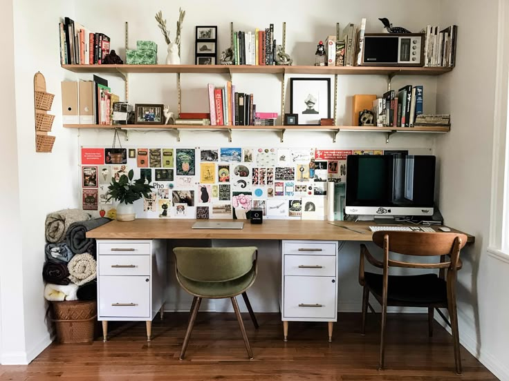 a desk with two chairs and a computer on top of it in front of a bookshelf