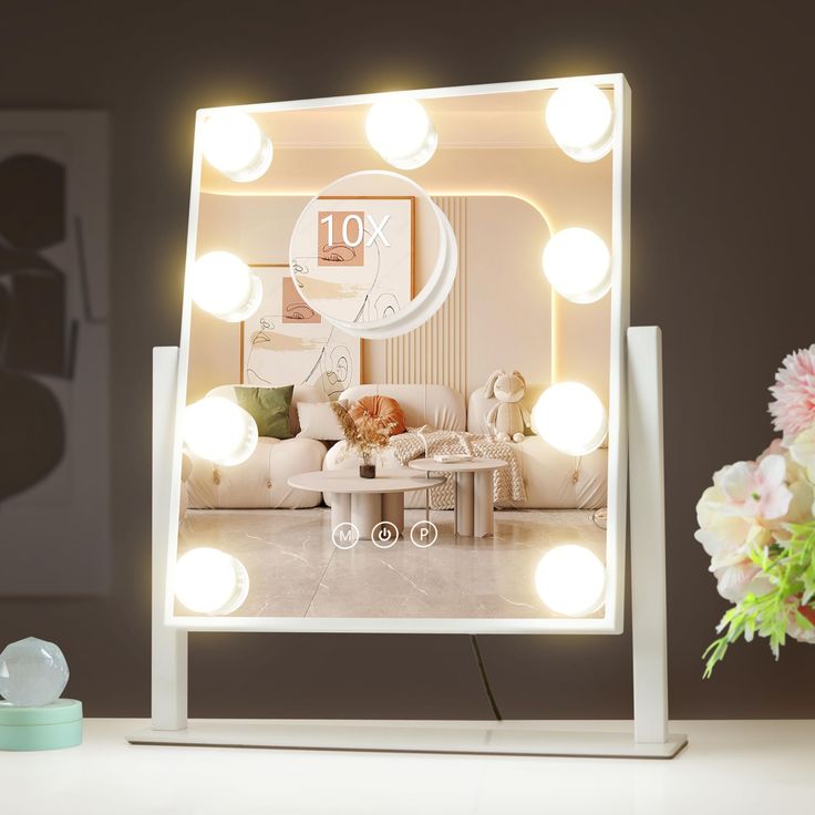 a mirror that has some lights on it in front of a table with flowers and vases