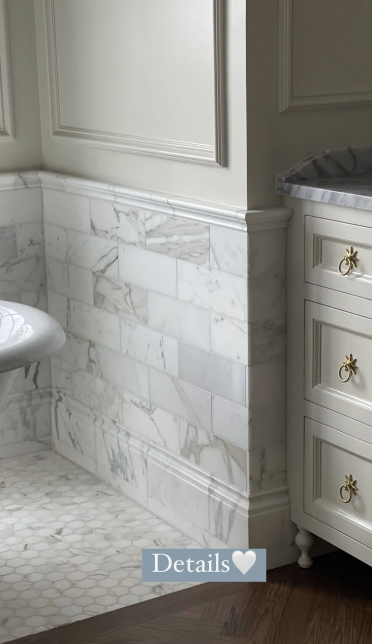 a bathroom with white cabinets and marble counter tops on the wall, next to a pedestal sink