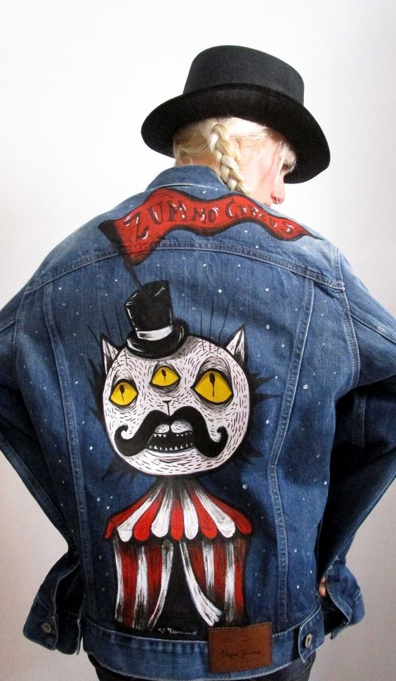 a person wearing a jean jacket with an image of a cat on it's back