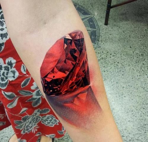 a red diamond tattoo on the arm