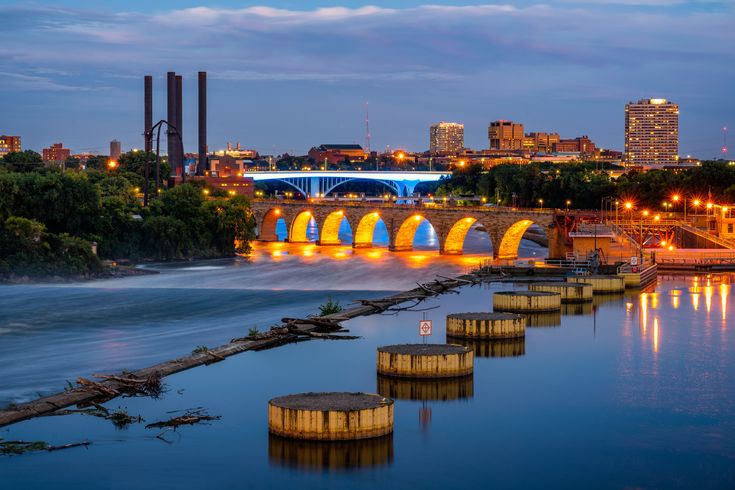 a bridge over a body of water at night with lights on and buildings in the background