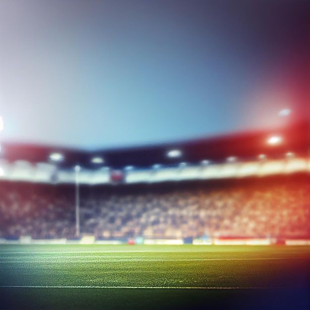 a blurry photo of a soccer field with the lights on and people in the stands