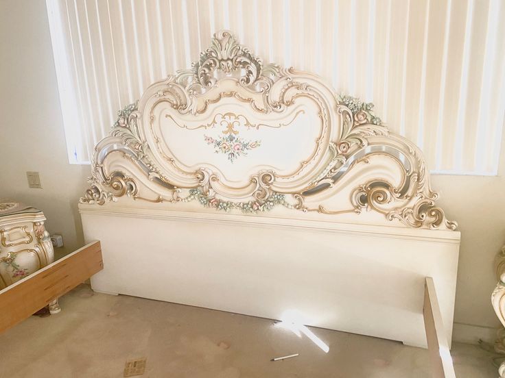 a white bed with ornate headboard and foot board sitting in a room next to other furniture