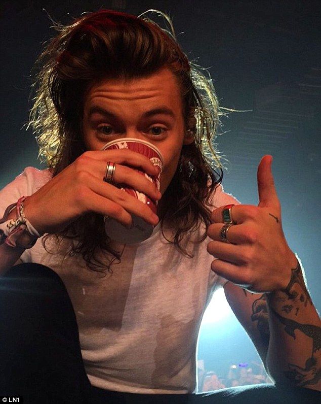 a man with long hair drinking from a cup