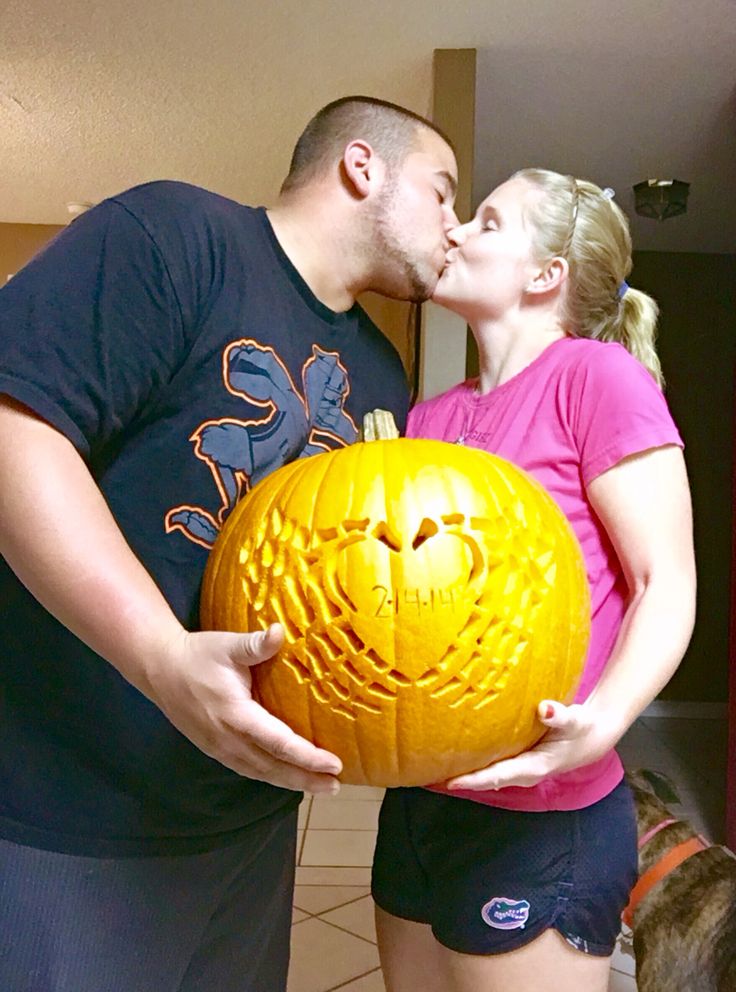 a man and woman kissing in front of a carved pumpkin