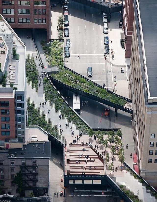 an aerial view of people walking on the sidewalk and cars driving down the street in front of tall buildings