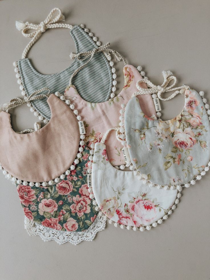 five bibs with flowers and lace on them