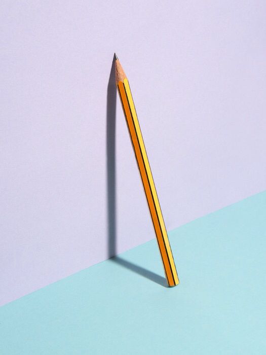 a pencil casting a shadow on a pastel background