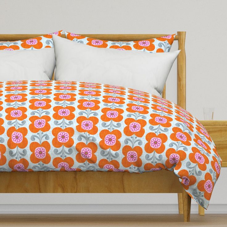 an orange and white bed with two pillows on top of it, next to a wooden headboard