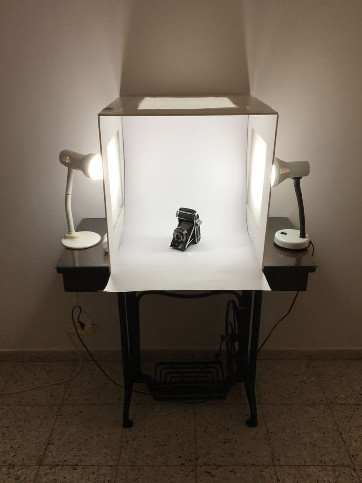 a camera is sitting on top of a table in front of a light box with two lamps