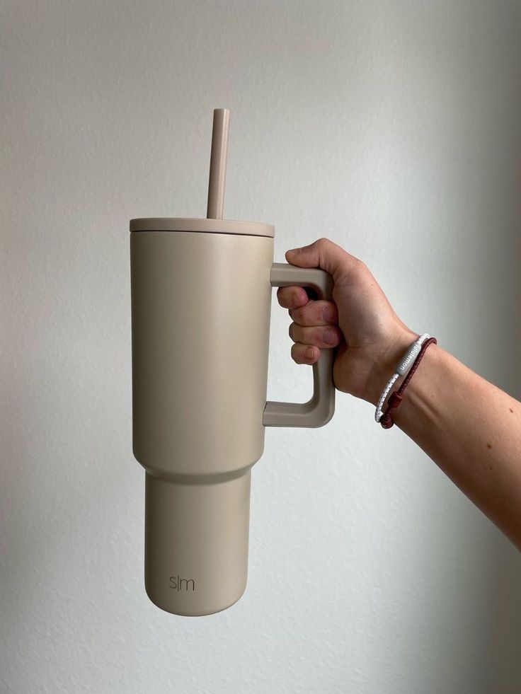 a hand holding a coffee cup with a straw sticking out of it