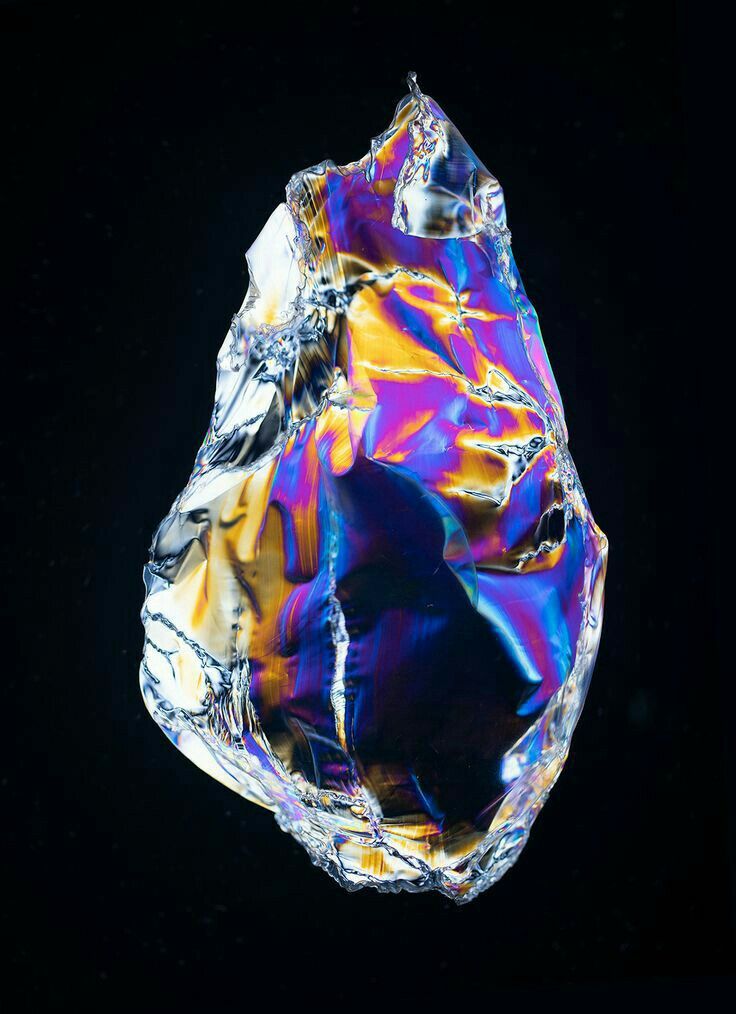 a colorful piece of glass sitting on top of a black surface with no one around it