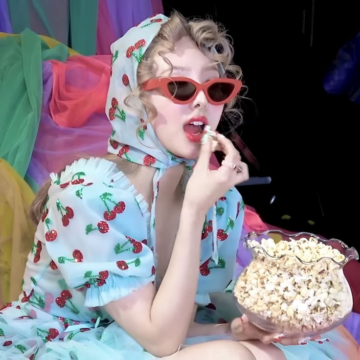 a woman in sunglasses and a dress eating popcorn