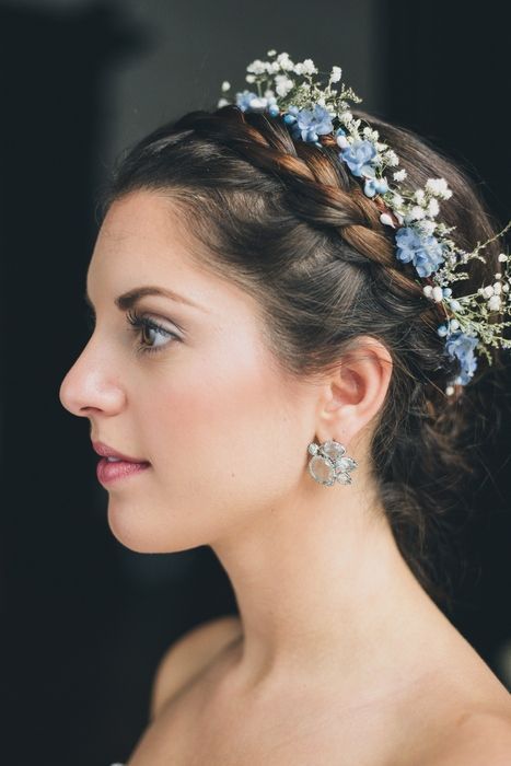 a woman wearing a blue flowered headpiece with hair pins in her hair is looking off to the side