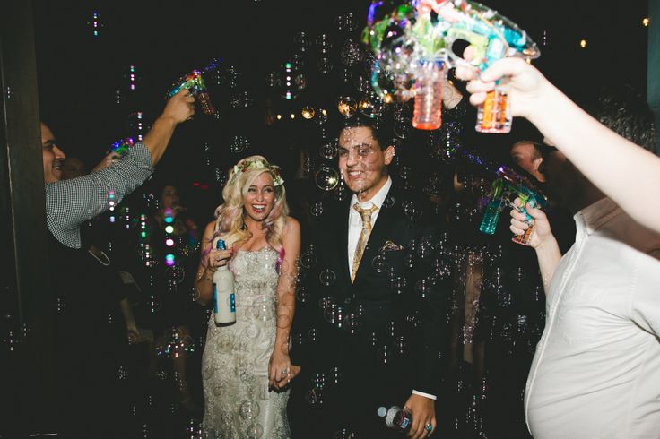 a group of people standing around each other at a party with bubbles in the air