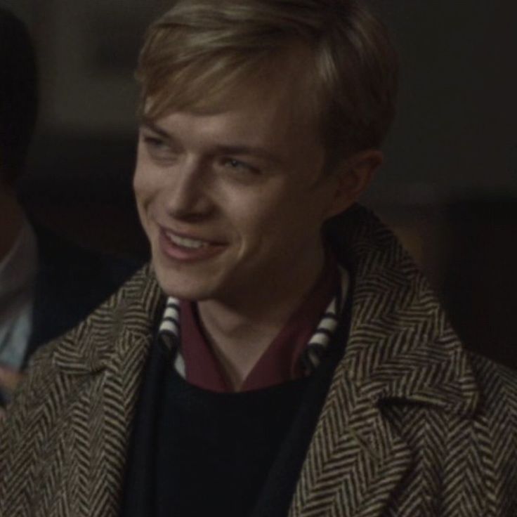 the young man is smiling and wearing a coat