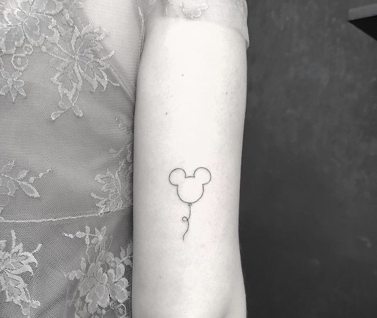 a woman's arm with a small tattoo of a mickey mouse head on it