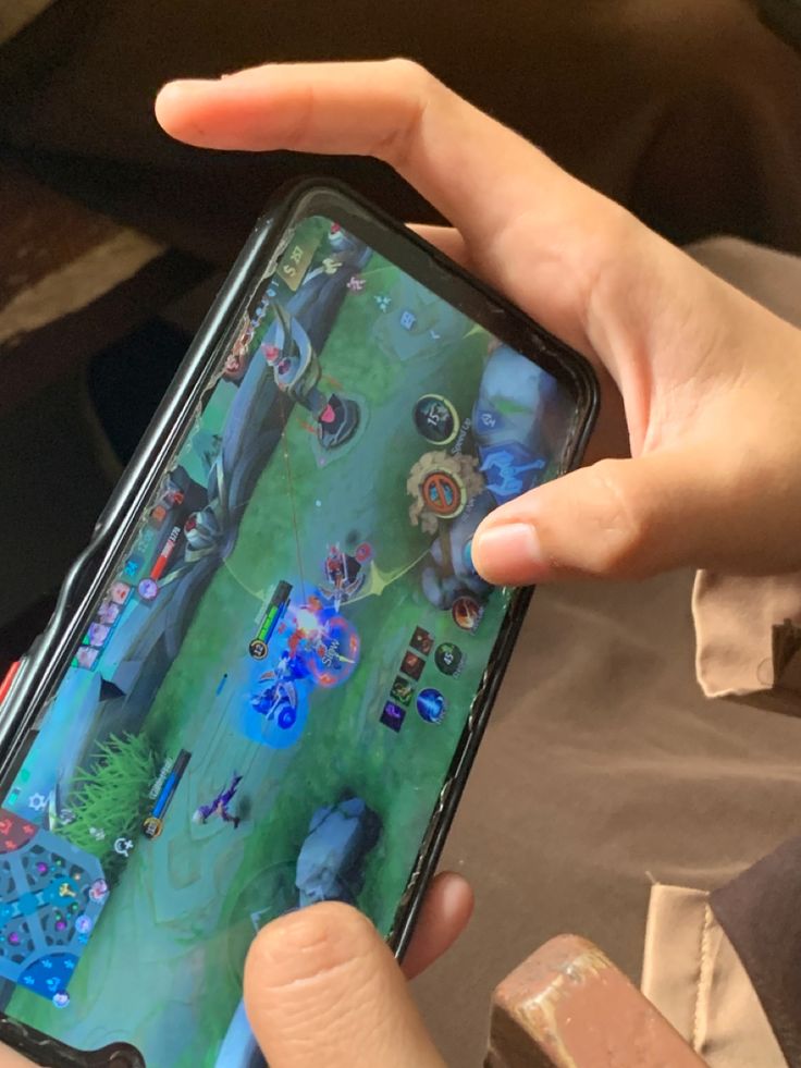 a person holding a cell phone in their left hand and playing an interactive game on the screen