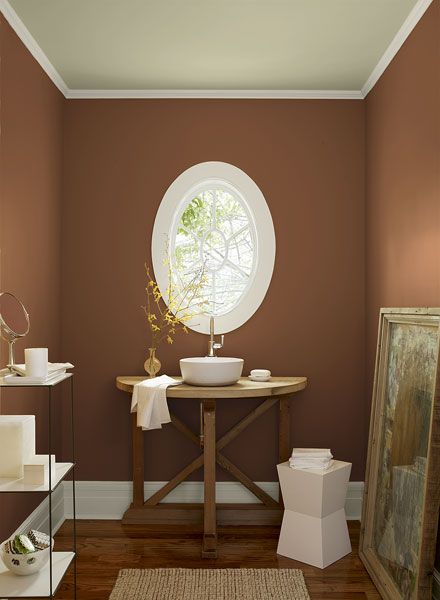 a bathroom with pink walls and white trim on the walls, along with a round window