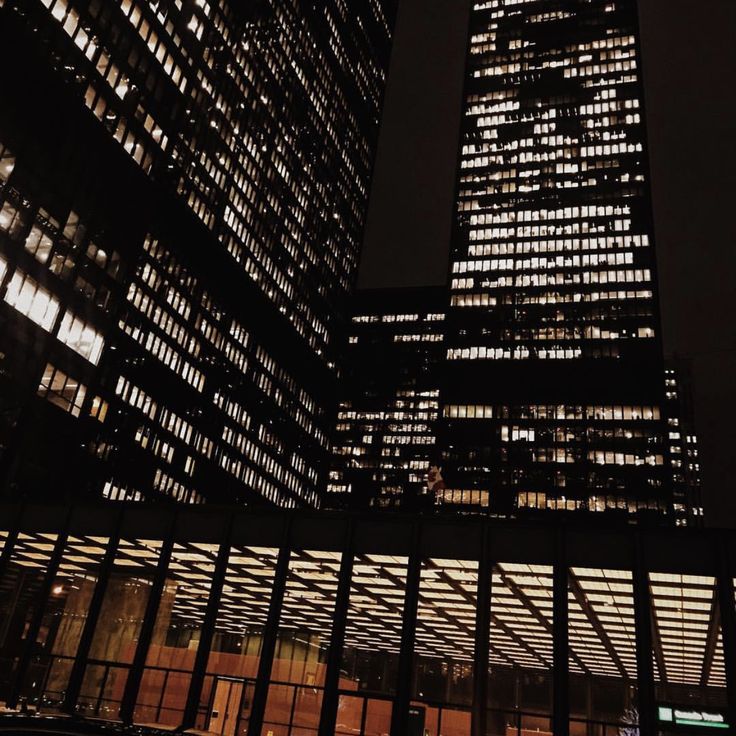 two tall buildings are lit up at night