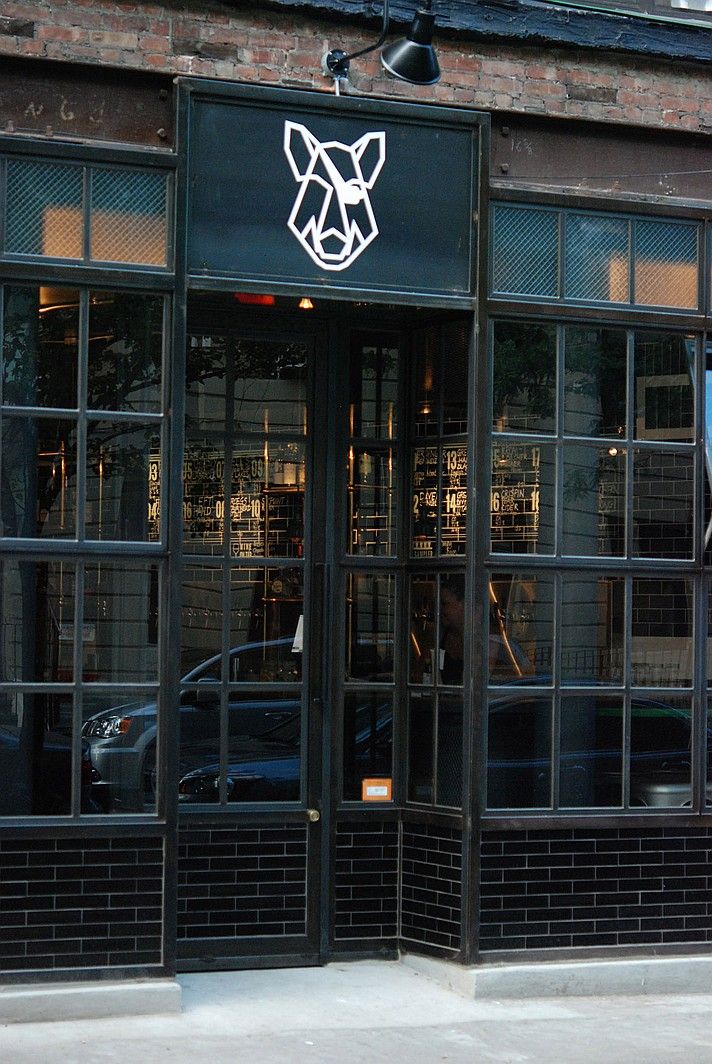 the front entrance to a restaurant with black doors and glass windows that have a dog's head on it