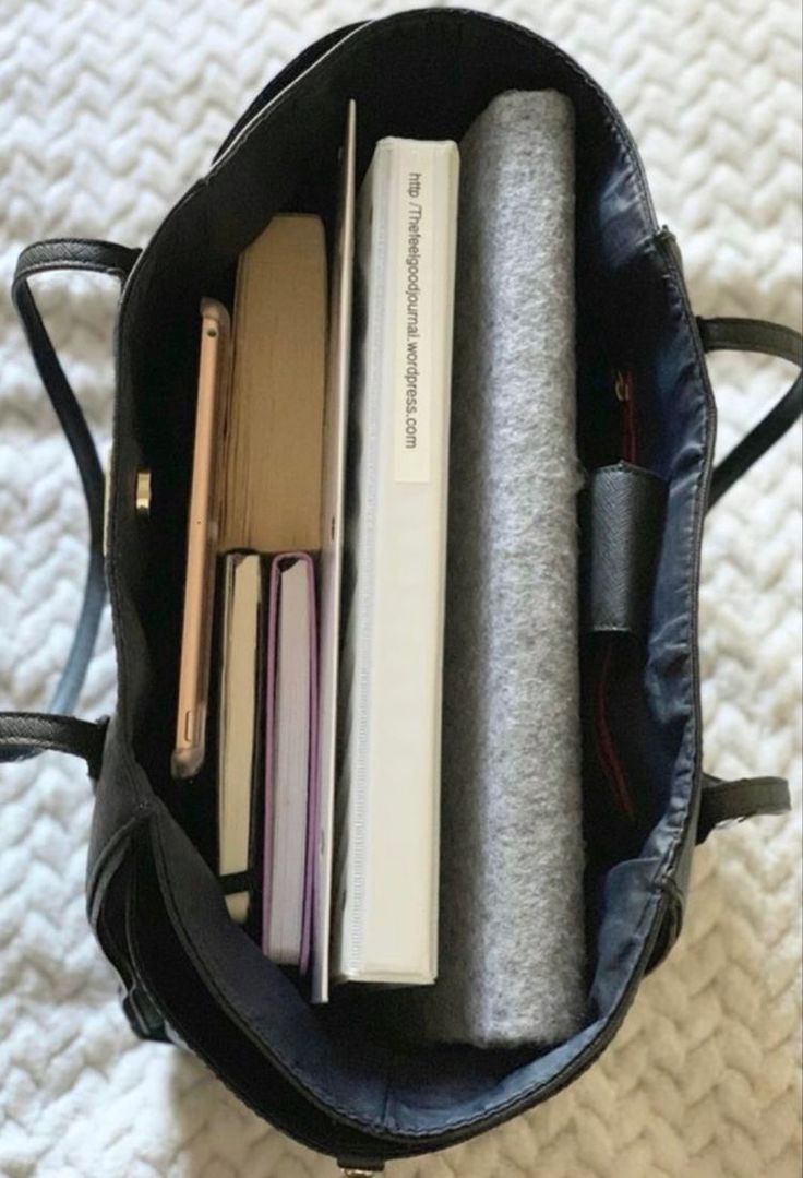 an open book bag filled with books on top of a bed