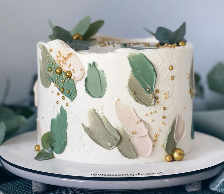 a close up of a cake on a plate with green leaves and gold beads around it