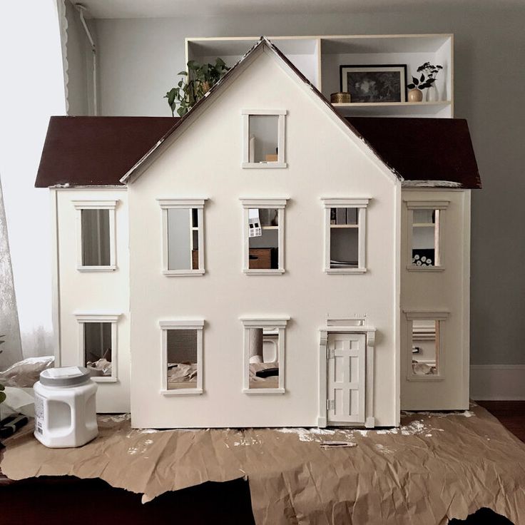 a doll house sitting on top of a piece of cardboard next to a window and door