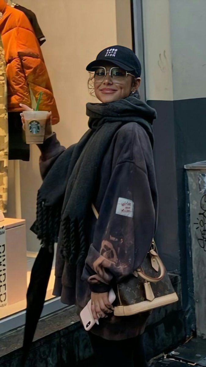 a woman is walking down the street with her handbag and coffee in her other hand