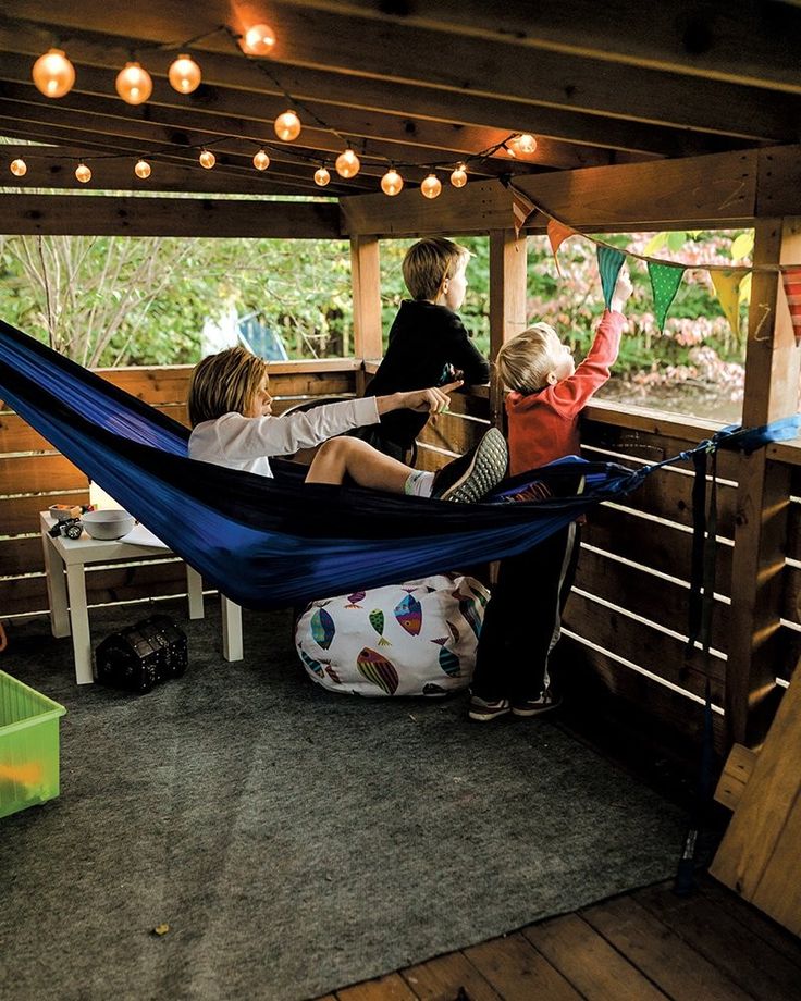 three people are sitting in a hammock