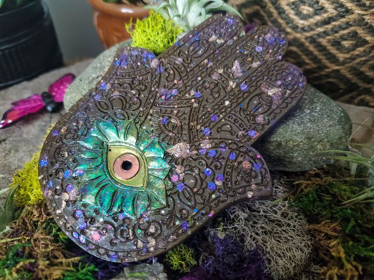 a close up of a decorative object on a rock with plants and rocks in the background