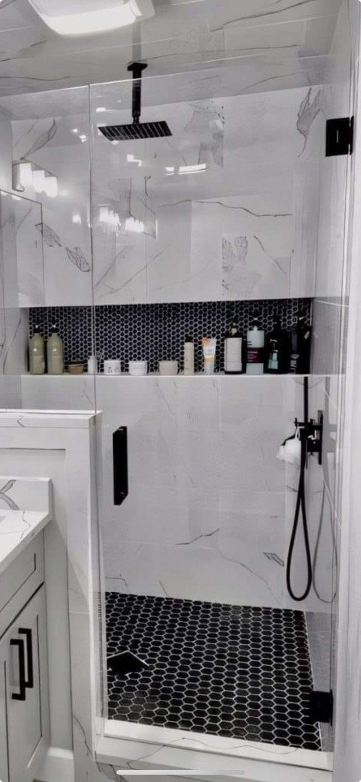 a white bathroom with black and white tiles on the shower wall, toilet and sink