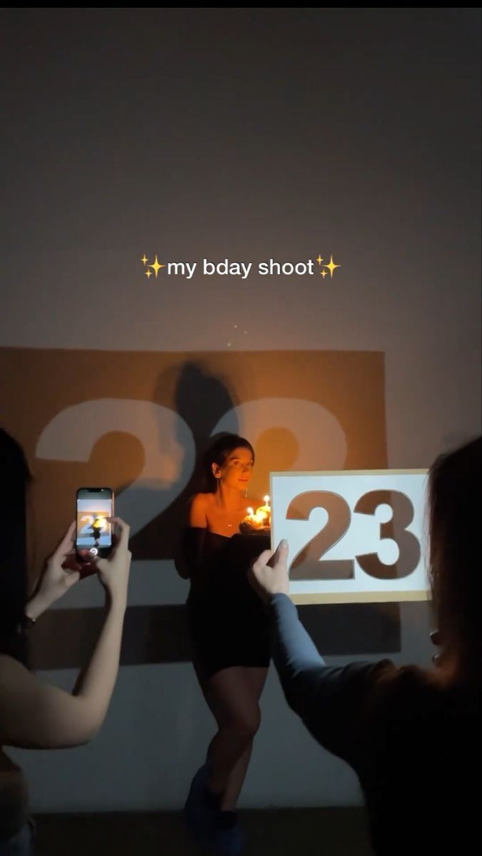 two women taking pictures with their cell phones in front of a screen that says, my body shoot