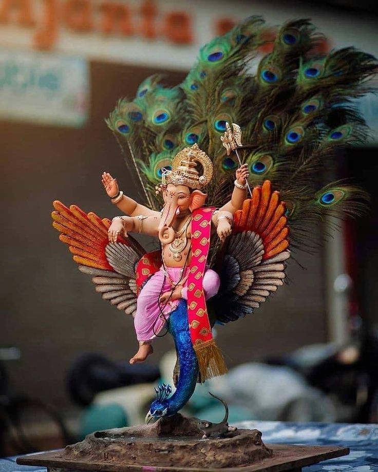 a figurine of a man with peacock feathers on his head and arms outstretched